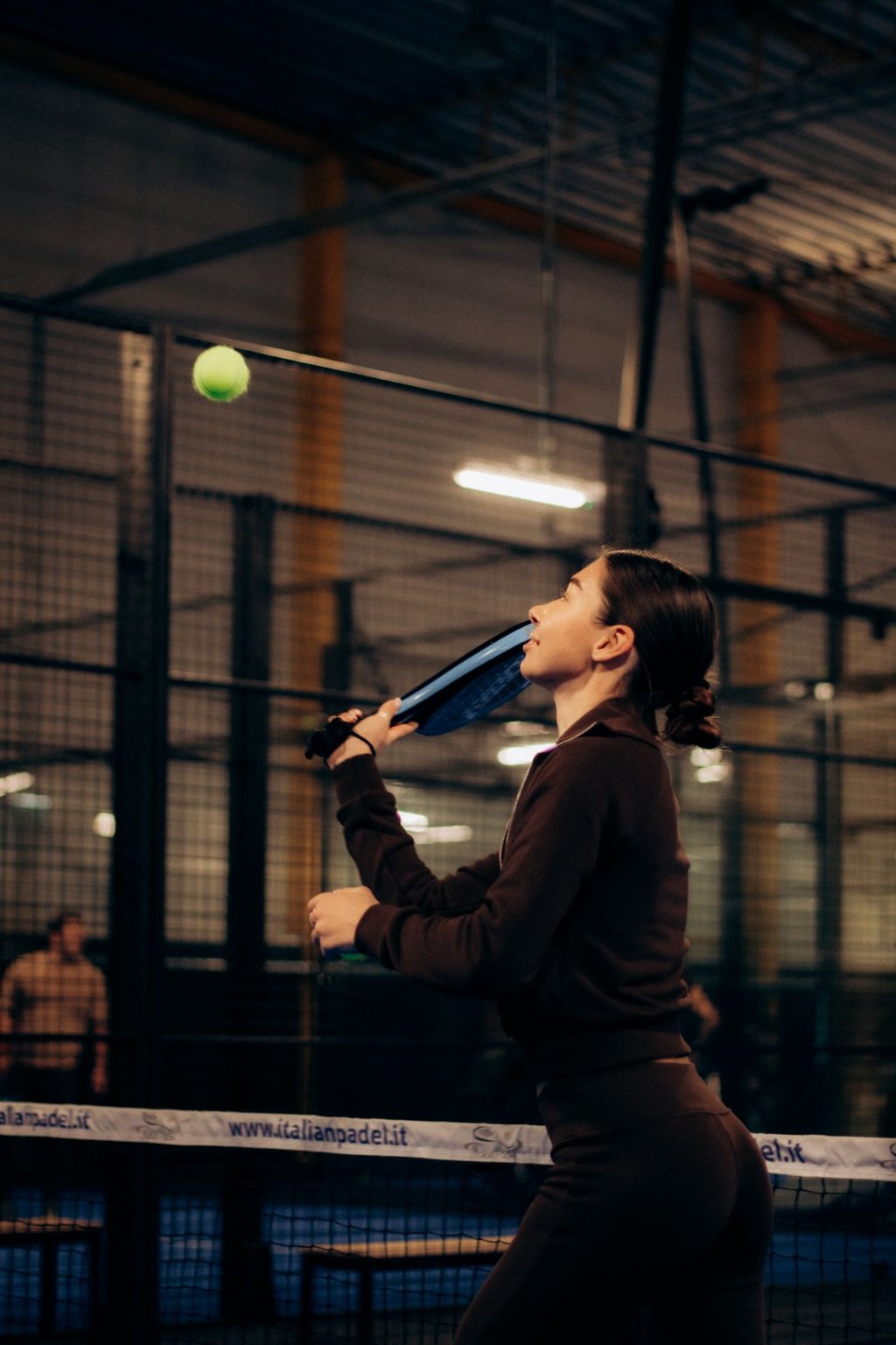 Player preparing to serve on an indoor padel court